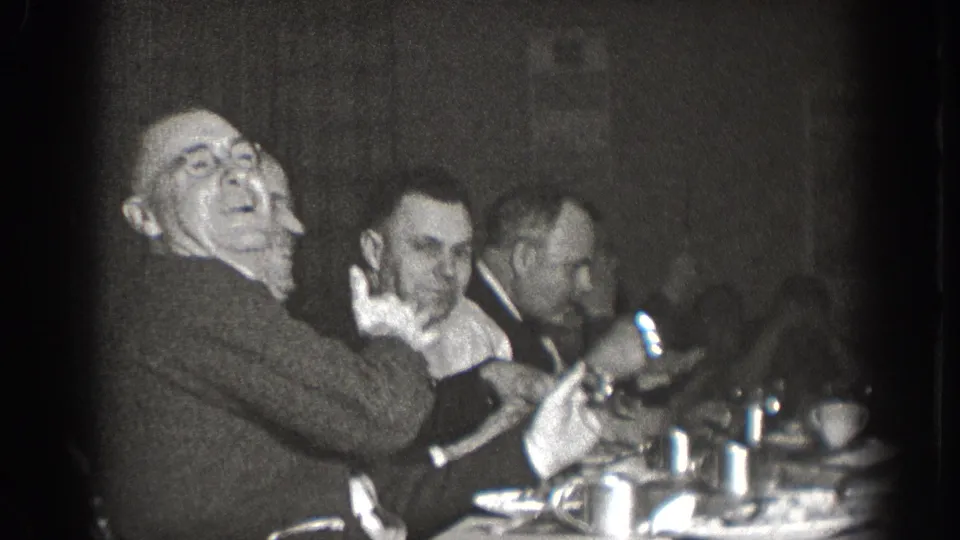 Group of men in 1930s suits and ties at a dinner table in Chelan, Washington, one laughing openly, cups and dishware on table, 8mm home movie circa 1939.