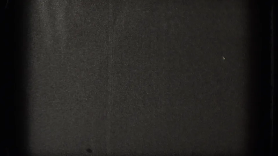 Almost completely dark frame at clip end; severe underexposure leaves no legible subject, typical of 8mm home-movie footage at reel transition.