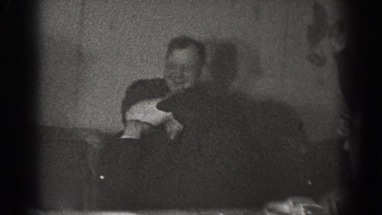 The final frame shows adult men in a dim Chelan interior, with one man seated or bent low while another leans over him during the playful interaction.