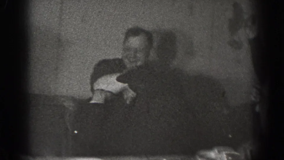 The final frame shows adult men in a dim Chelan interior, with one man seated or bent low while another leans over him during the playful interaction.
