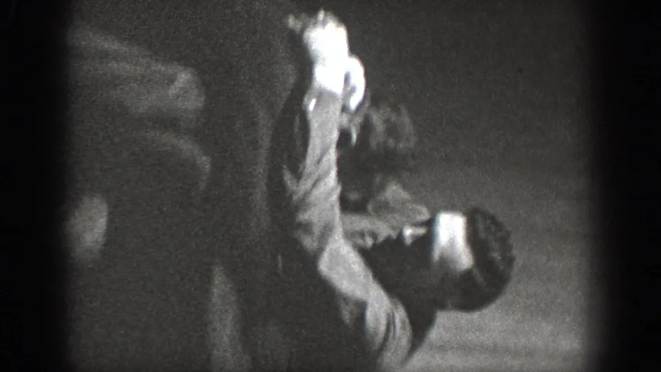 A person in a bent or crouching posture in a dark domestic interior; light areas on clothing contrast with heavily shadowed surroundings, ca. 1939.