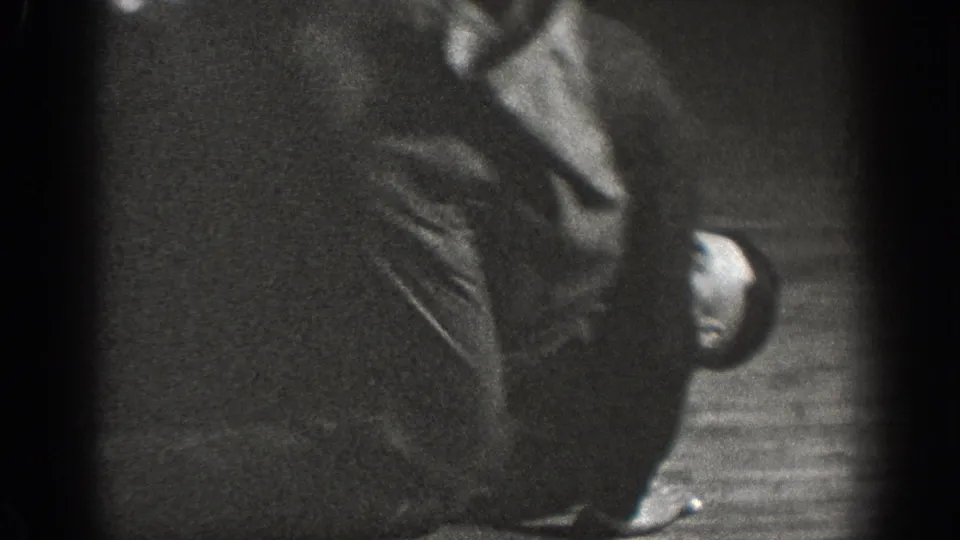 A near-silhouette figure in dark period clothing in a domestic interior; extreme underexposure limits visible detail, ca. 1939.