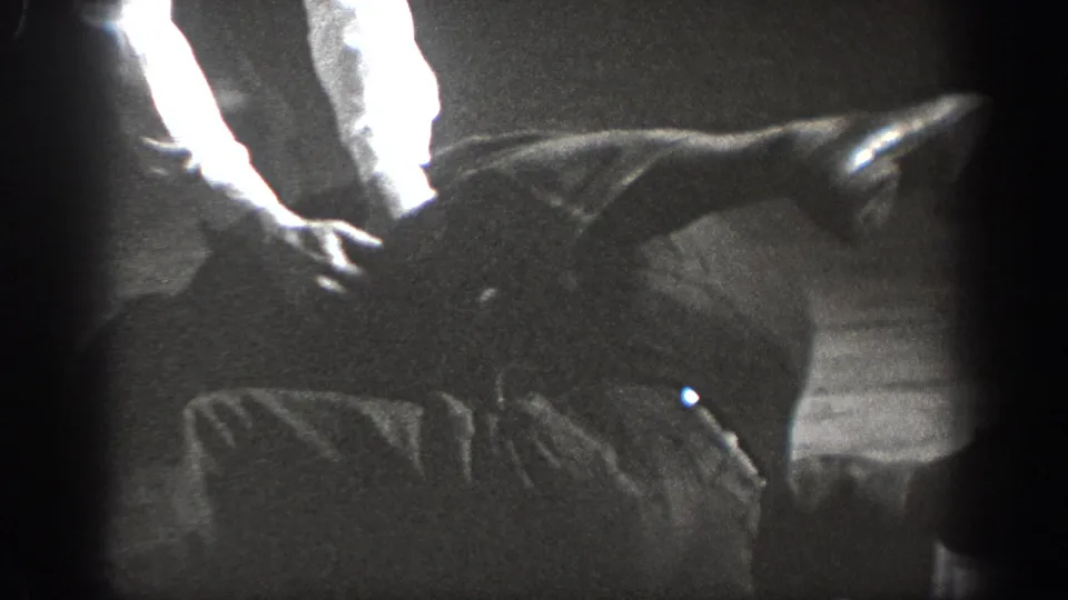 Extreme close-up of young men wrestling on an indoor wooden floor, Chelan, Washington, circa 1939, on 8mm home movie film.