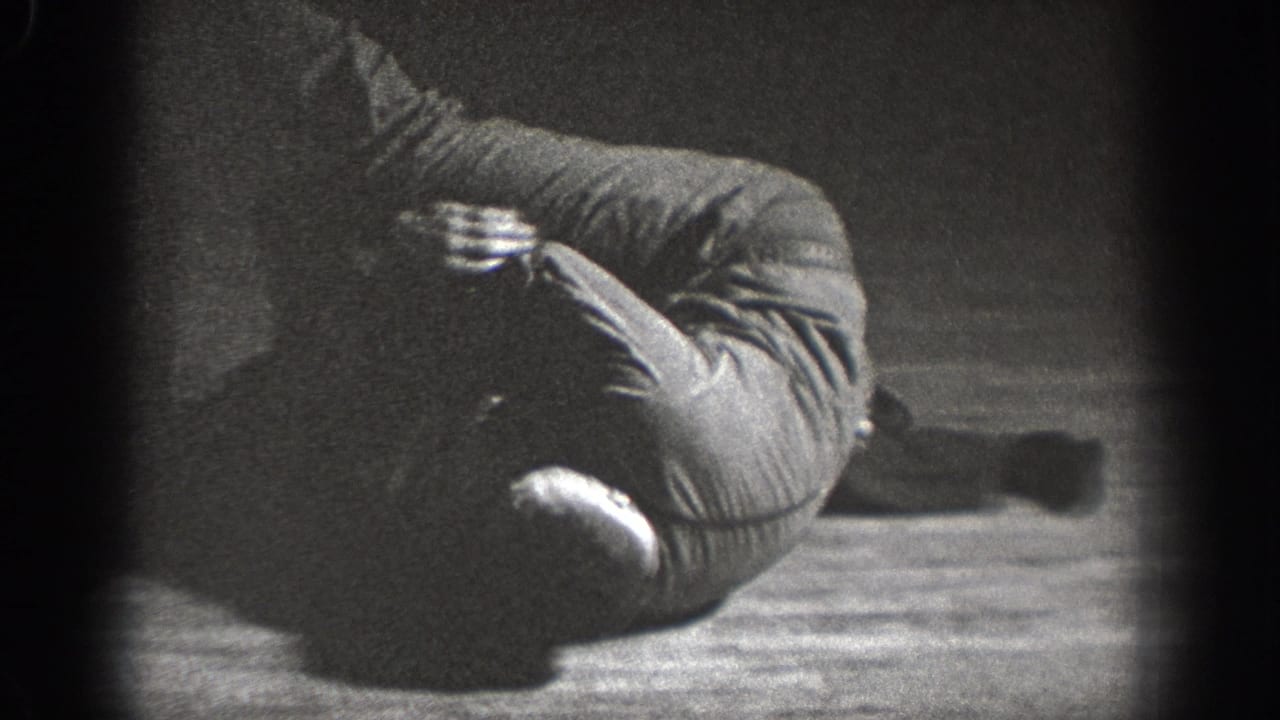 Young man crouched defensively on a wooden floor in dark clothing, Chelan, Washington, circa 1939, 8mm home movie.