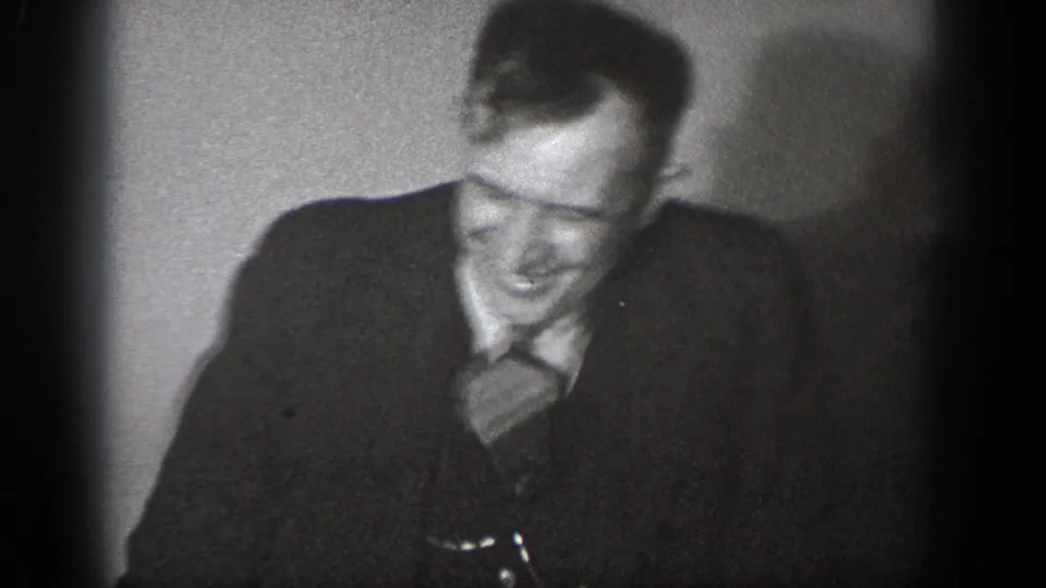 Close-medium shot of a man in 1930s suit and tie laughing broadly, from a 1939 8mm home movie, Chelan, Washington.