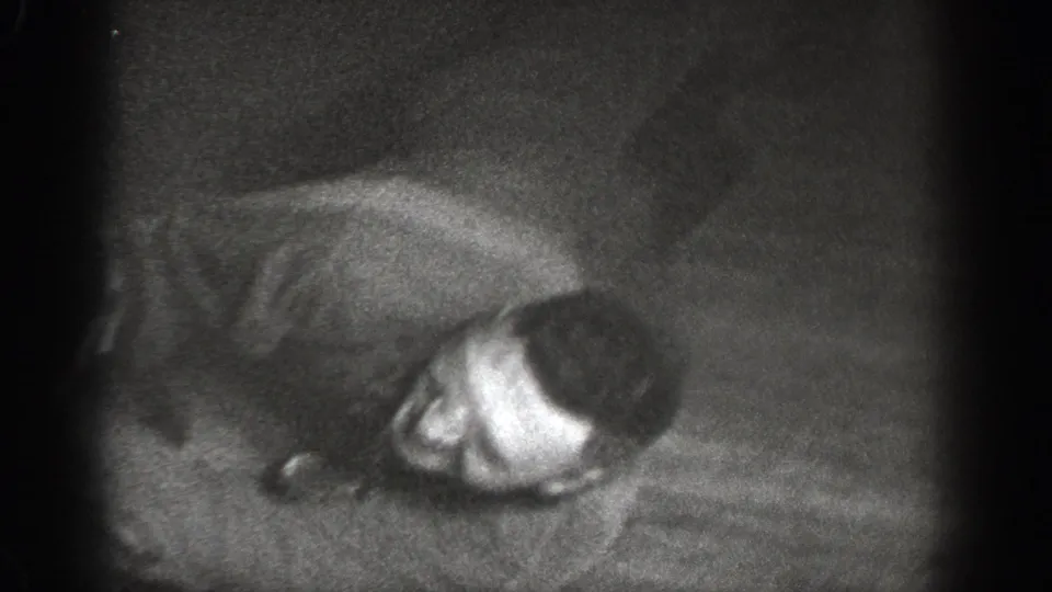 Overhead shot of man lying on wood floor with relaxed or laughing expression; 8mm home movie, Chelan, Washington, circa 1939.