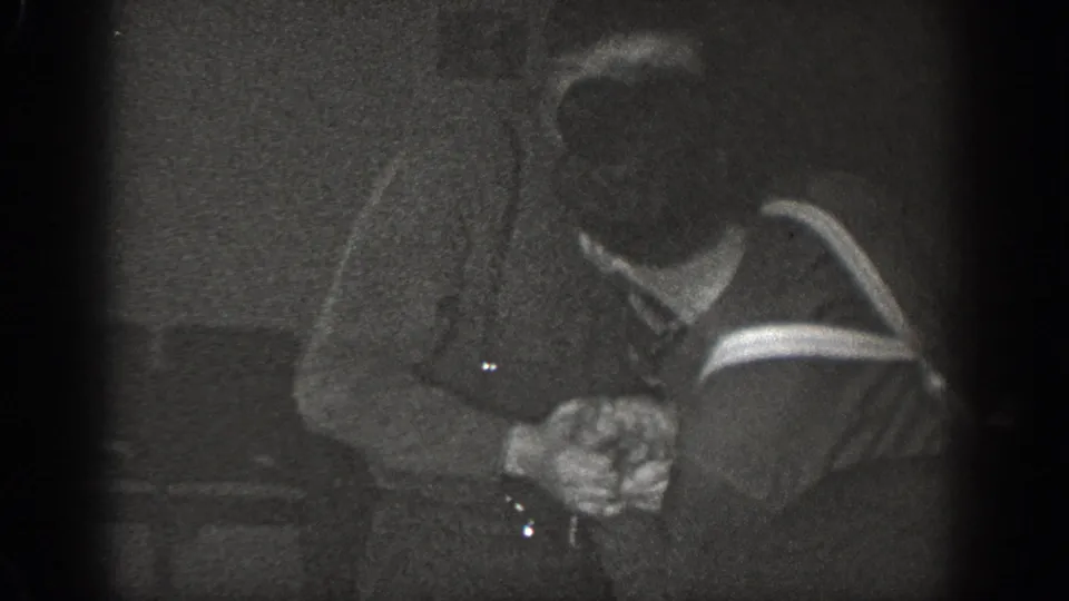 Two men with clasped hands in a dark interior, one in a striped sweater; 8mm home movie, Chelan, Washington, circa 1939.