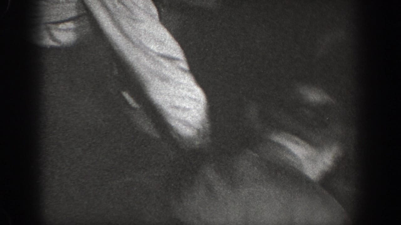 Close-up of a figure in light-colored clothing, heavily motion-blurred, black-and-white 8mm frame.