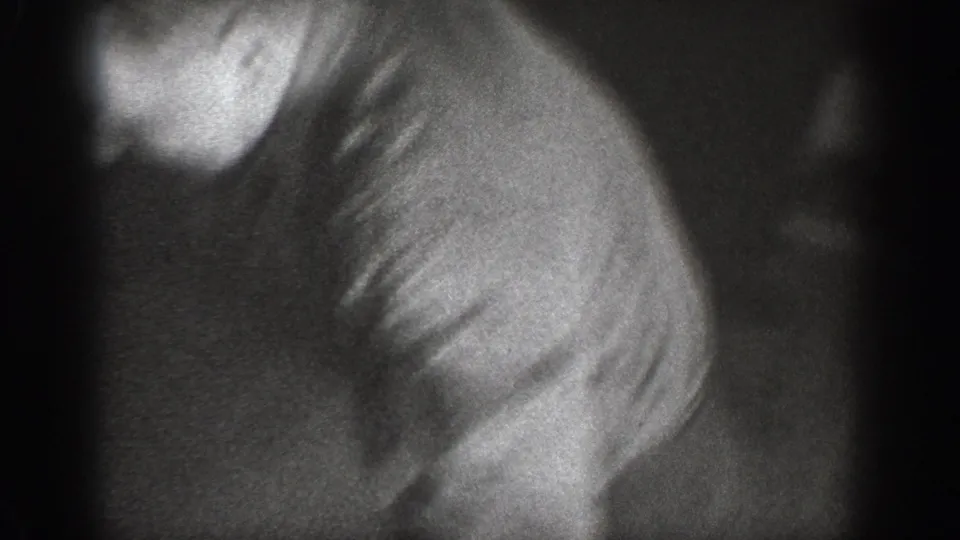 8mm home movie frame circa 1939, person in light-colored shirt bent or falling forward in a dark interior, head partially visible with heavy motion blur.