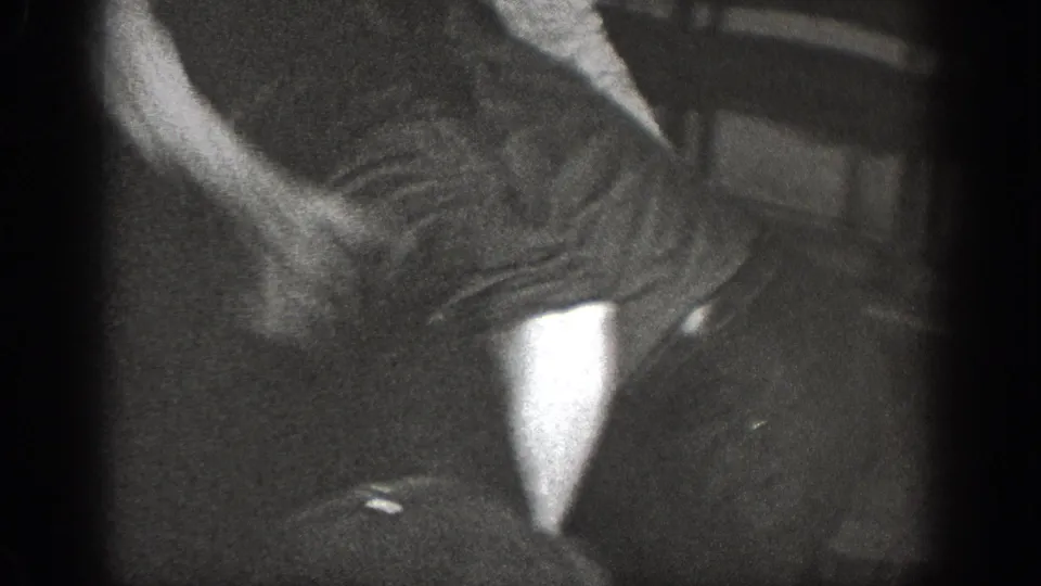 8mm home movie frame circa 1939, lower body and legs in rapid motion in a dark indoor space, pale object on the floor and high grain throughout.