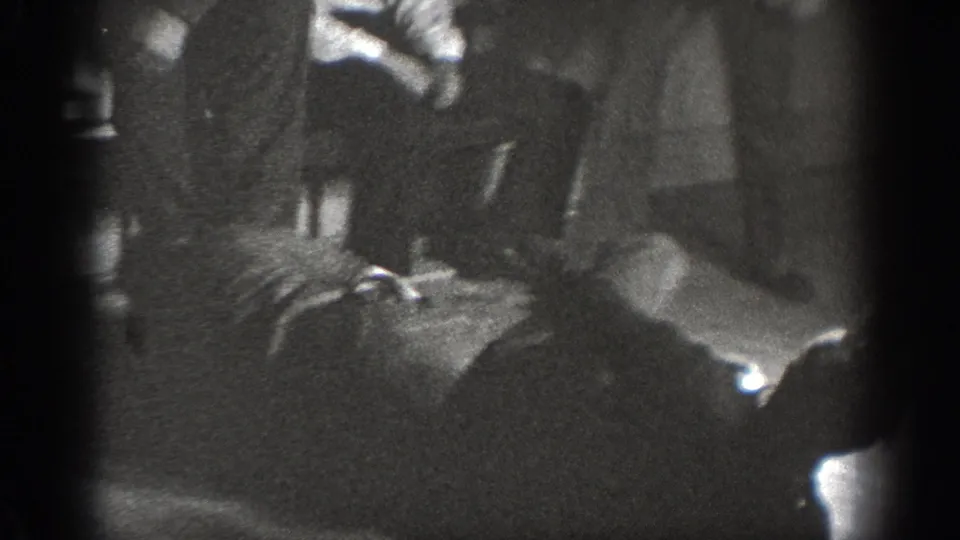 Dark, grainy 8mm home-movie frame from around 1939 showing men wrestling or grappling in a dimly lit indoor space in Chelan, Washington.