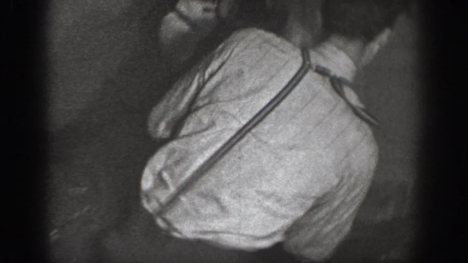 Close-up of a man in a striped work shirt caught mid-action during horseplay, dress consistent with late-1930s working-class style; 8mm film stock with heavy vignetting.