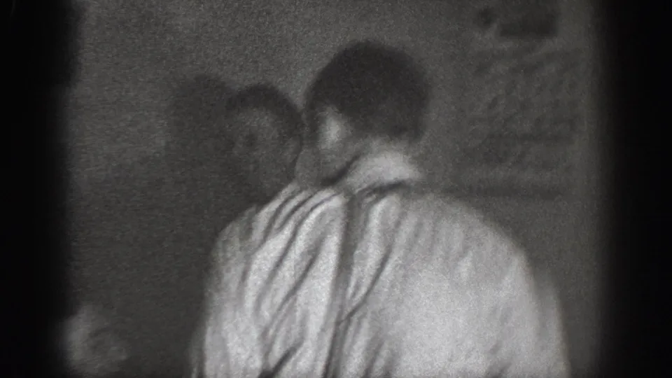 Two adult men in light shirts engaged in physical horseplay against a dark interior background, consistent with a 1930s Pacific Northwest domestic or workshop setting.