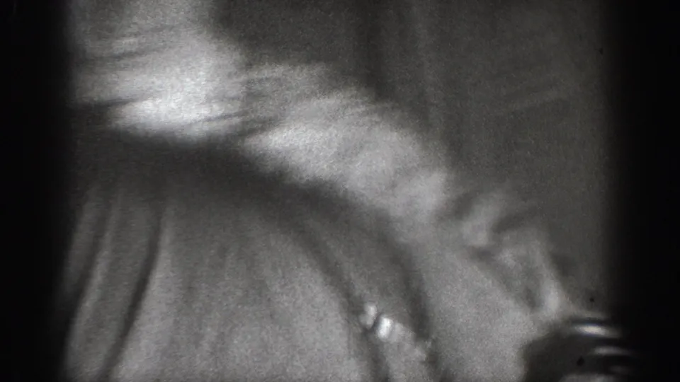 Motion-blurred 8mm frame, ca. 1939: close-up of dark clothing on a figure's back or shoulder during physical altercation, Chelan, Washington.