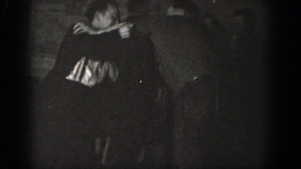 Two men locked in a close clinch, one in a striped shirt; underexposed 8mm home-movie footage, possibly Chelan, Washington, circa 1939.