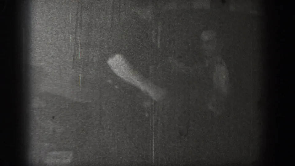 Near-silhouette of one figure with raised arm against a dark wall; final frame of the 8mm clip, likely circa 1939, Chelan, Washington.