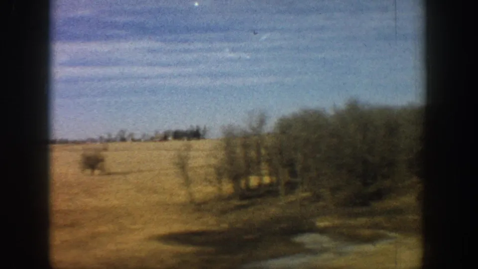 Rolling dry hills and bare trees along a ridgeline, open fields extending to the horizon; 8mm road-trip footage consistent with rural Colorado, circa 1961.
