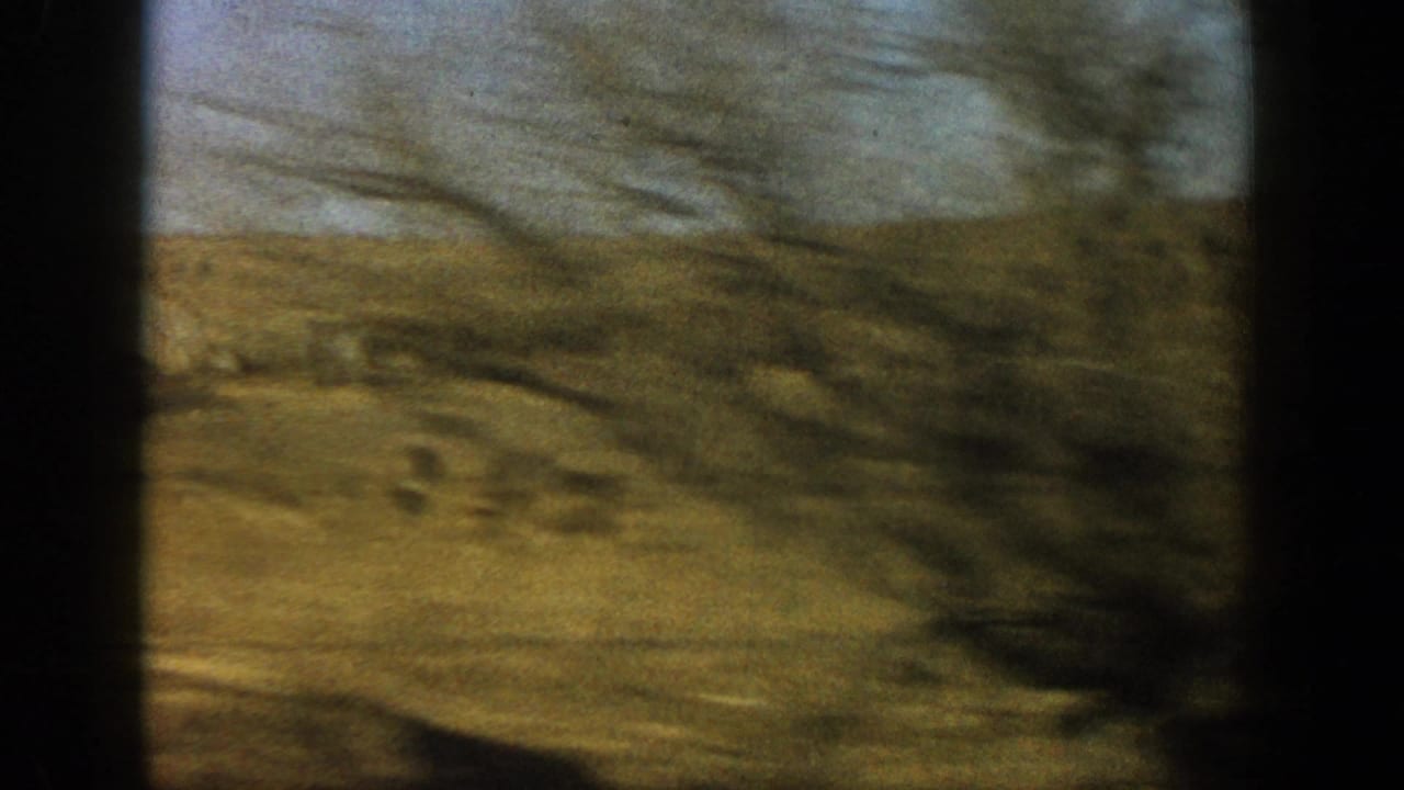 Motion-blurred 8mm pan across golden-brown and olive grassland, consistent with a rural Colorado setting circa 1961.