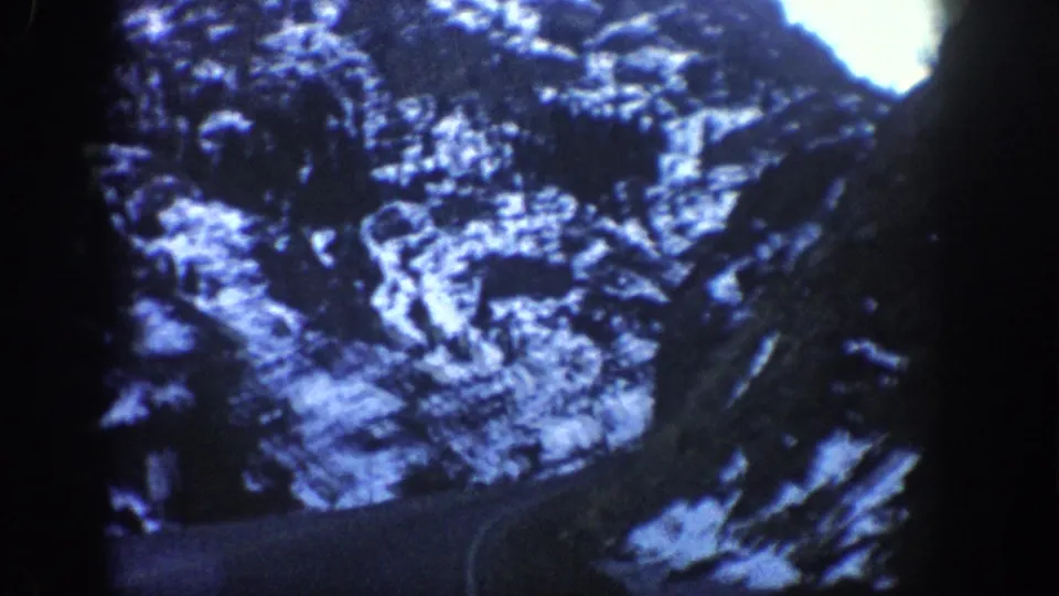 8mm shot of rugged snow-covered mountain terrain near a tunnel exit, bright sky visible at upper right, circa 1961 Colorado Rockies