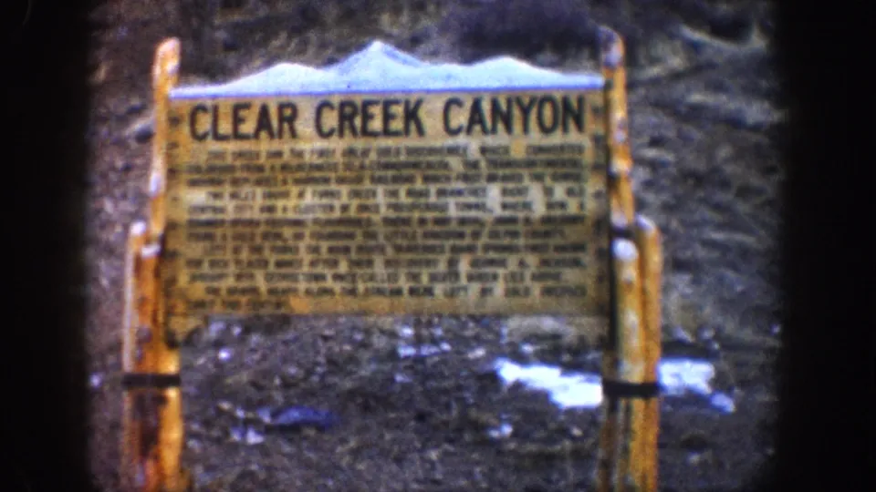 Clear Creek Canyon historical wayside marker, Colorado, circa 1961, wooden framed sign with multi-line interpretive text and snow-patched ground visible in the background.