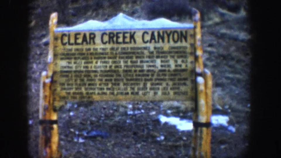 Clear Creek Canyon wayside marker, Colorado, circa 1961, held or repeated shot of the wooden interpretive sign with historical text in 8mm home-movie color.