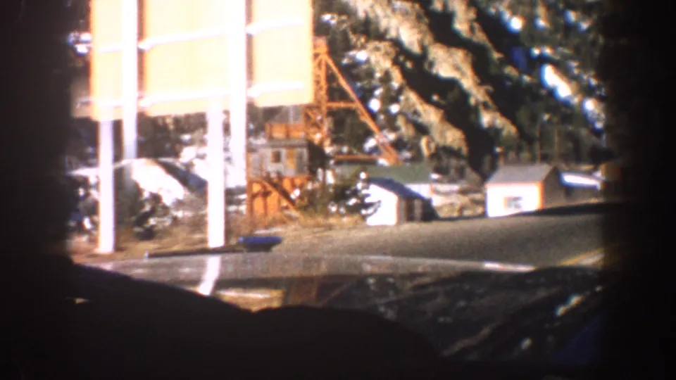 Mid-century commercial or lodge building with white columns and a red metal structure alongside, snow-covered ground and conifers, Aspen, Colorado, 1961.