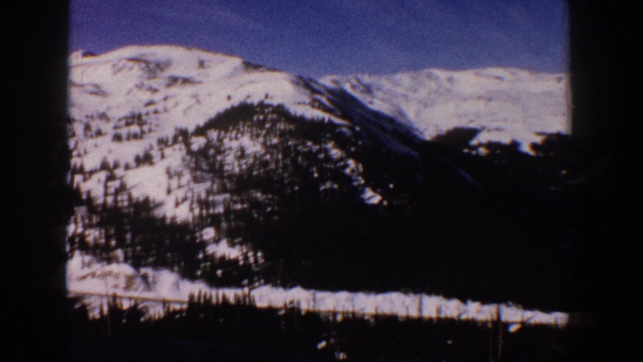 View from a moving vehicle of snow-covered Rocky Mountain peaks near Aspen, Colorado, circa 1961, shot on 8mm film.