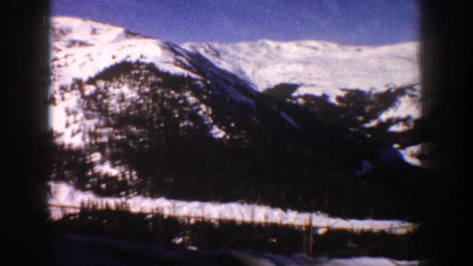 8mm pan shot of snow-covered Rocky Mountain ridge near Aspen, Colorado, circa 1961, showing forested slopes and clear blue sky.
