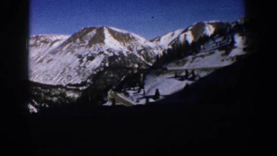 Prominent snow-capped Rocky Mountain peak under deep blue sky near Aspen, Colorado, circa 1961, with cleared slope and conifer treeline below.