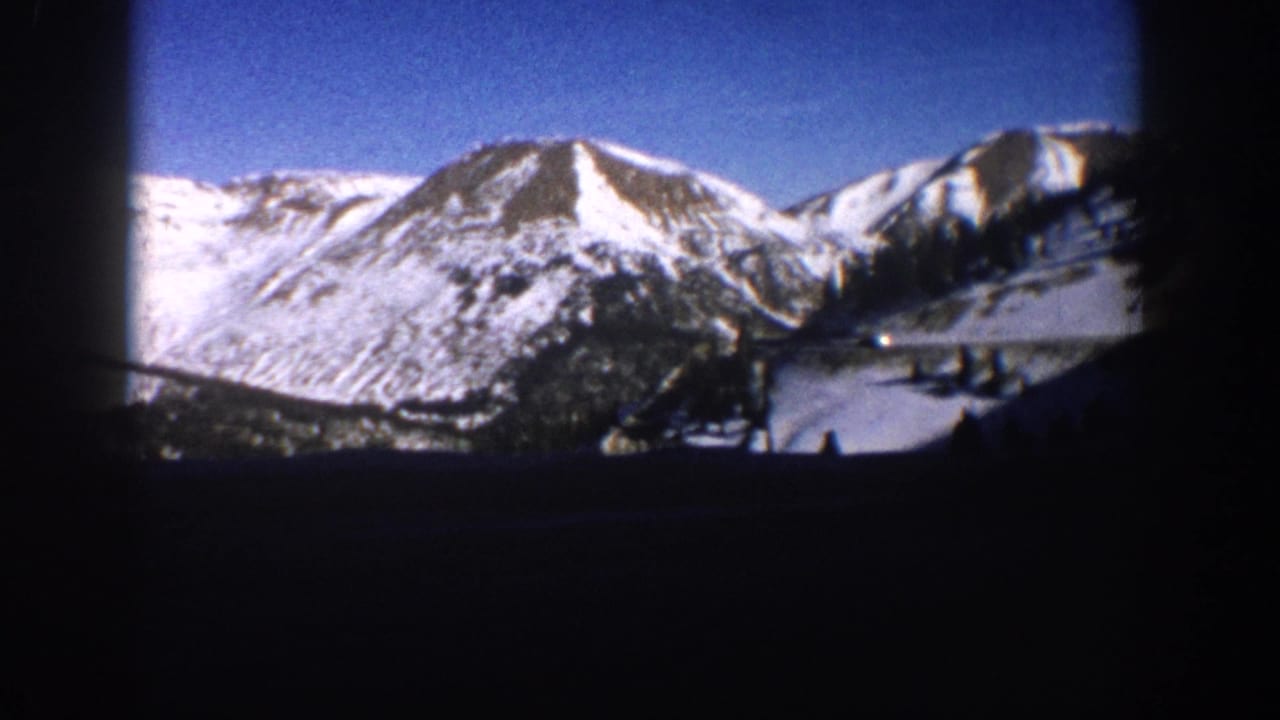 8mm home movie frame of snow-capped mountain peaks and forested lower slopes in the Aspen, Colorado area, circa 1961.