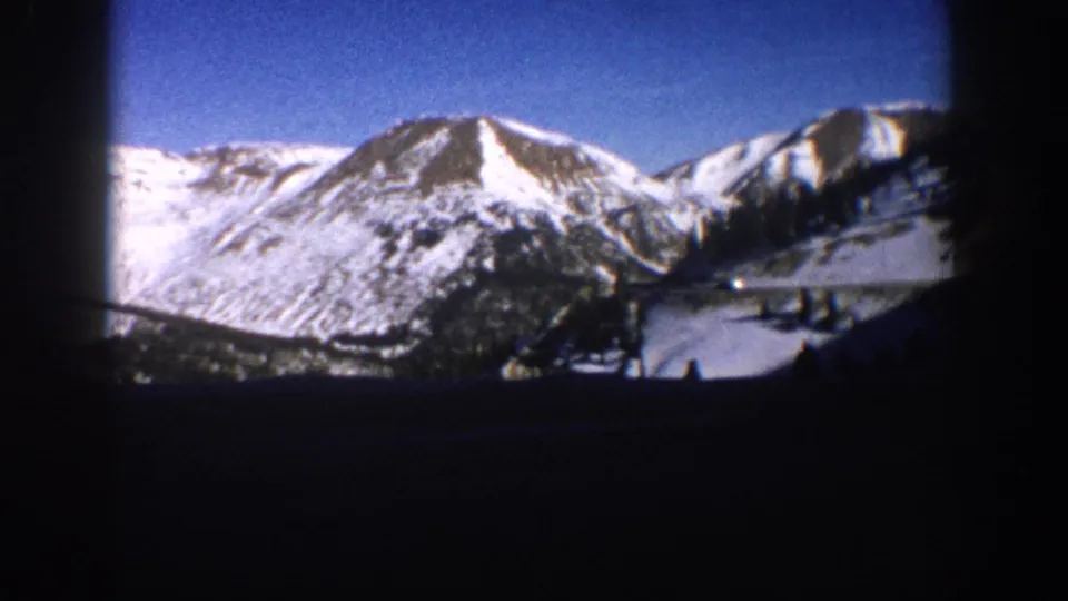8mm home movie frame of snow-capped mountain peaks and forested lower slopes in the Aspen, Colorado area, circa 1961.