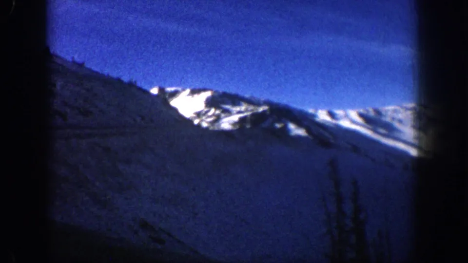 8mm home movie frame showing a snow-covered ridge dominating the frame, likely in the Colorado Rockies, circa 1961.