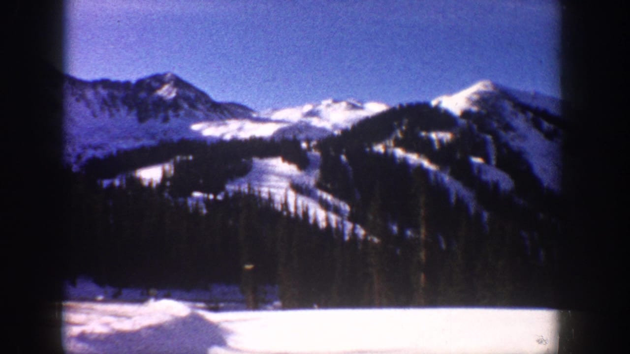 8mm home movie view through a moving vehicle window of snow-covered mountain peaks and apparent ski slopes, Aspen, Colorado, circa 1961.