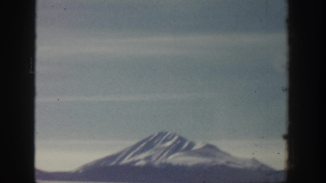 8mm home-movie frame showing a snow-covered peak, possibly in the Aspen area of Colorado circa 1961, with muted color palette from film aging.