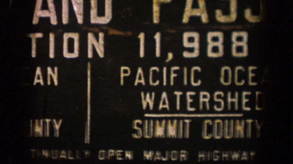1961 Colorado 8mm frame with a close, cropped view of the Pacific Ocean Watershed sign and partial Summit County lettering.