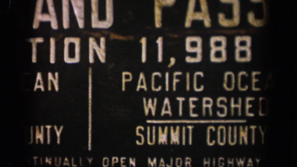 1961 Colorado 8mm frame showing a close, cropped view of a Summit County Pacific Ocean Watershed sign with population numbers.