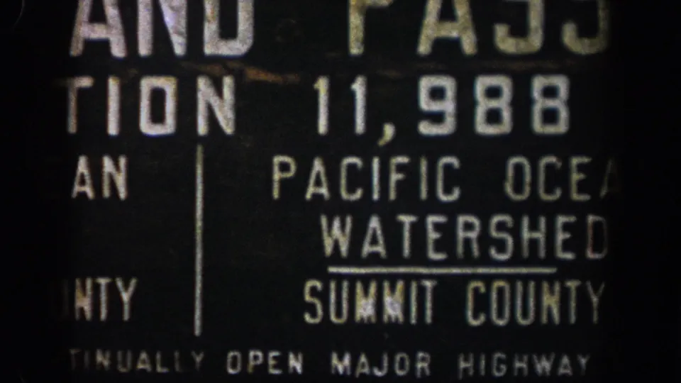 Close 1961 8mm view of a Colorado roadside sign, showing population 11,988 and Pacific Ocean Watershed wording.