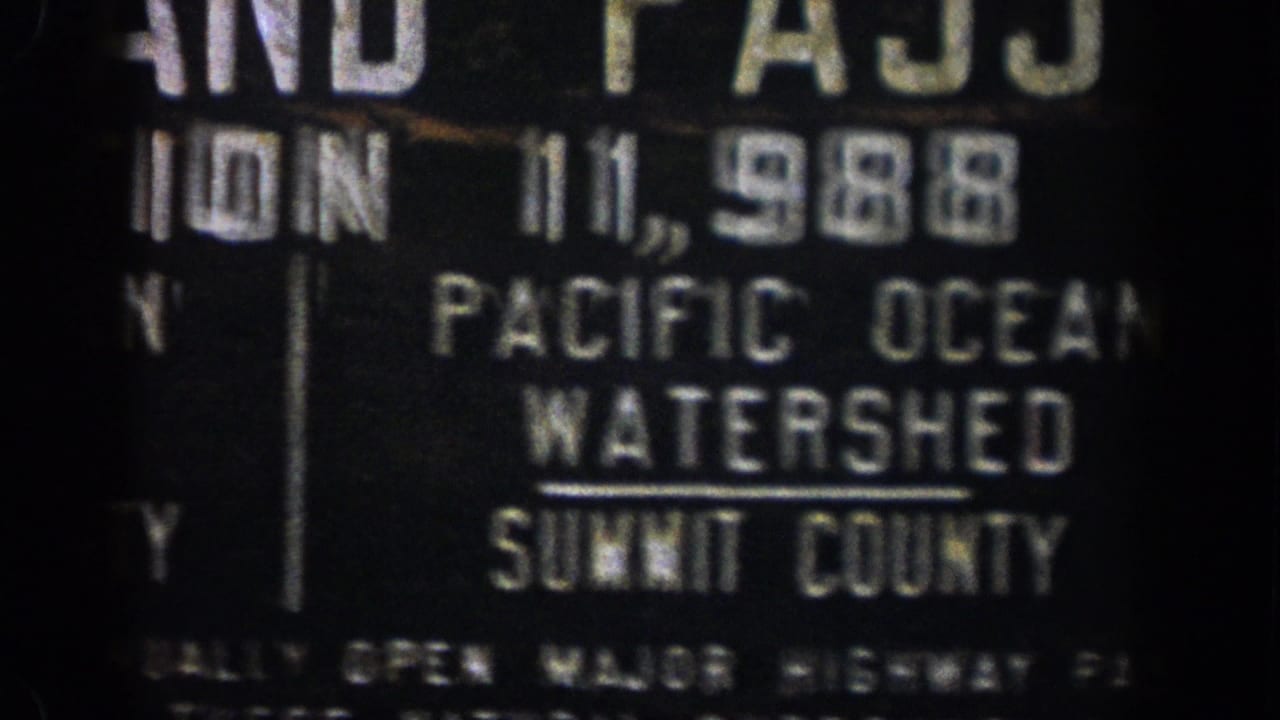 1961 Colorado 8mm frame of a dark roadside Pacific Ocean Watershed sign with Summit County text visible.