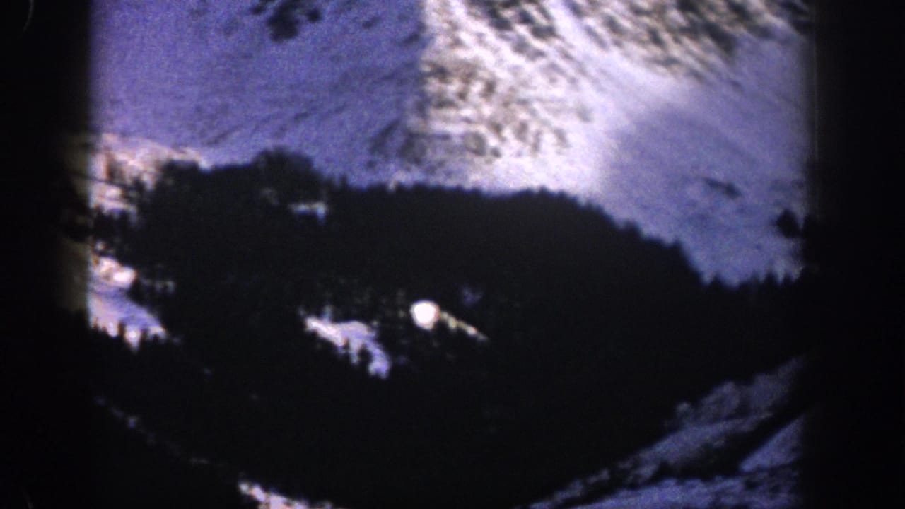 Aspen, Colorado 1961 home-movie view of a snow-dusted mountain slope and dark conifer forest from an elevated position.