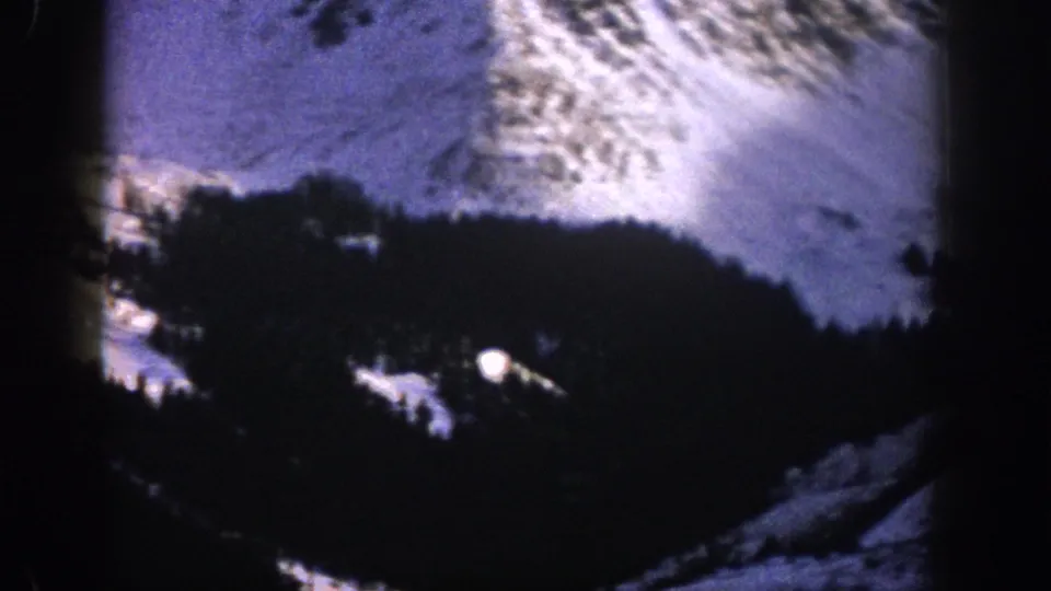 Aspen, Colorado 1961 home-movie view of a snow-dusted mountain slope and dark conifer forest from an elevated position.