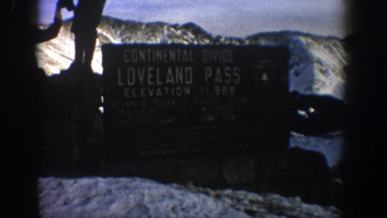 The Loveland Pass Continental Divide sign is filmed close-up against snow and distant peaks in 1961 8mm home-movie footage.