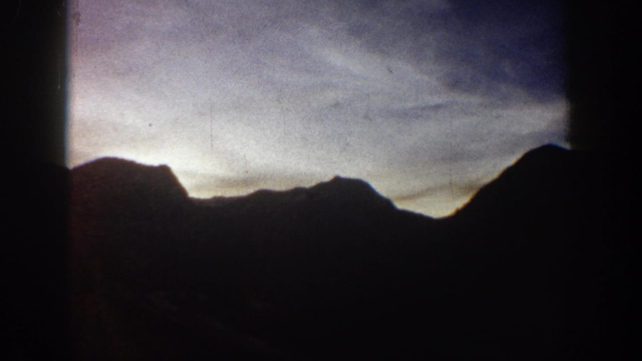 Rocky mountain ridge in silhouette against a purple-lavender twilight sky; 8mm home movie circa 1961, Aspen, Colorado area.