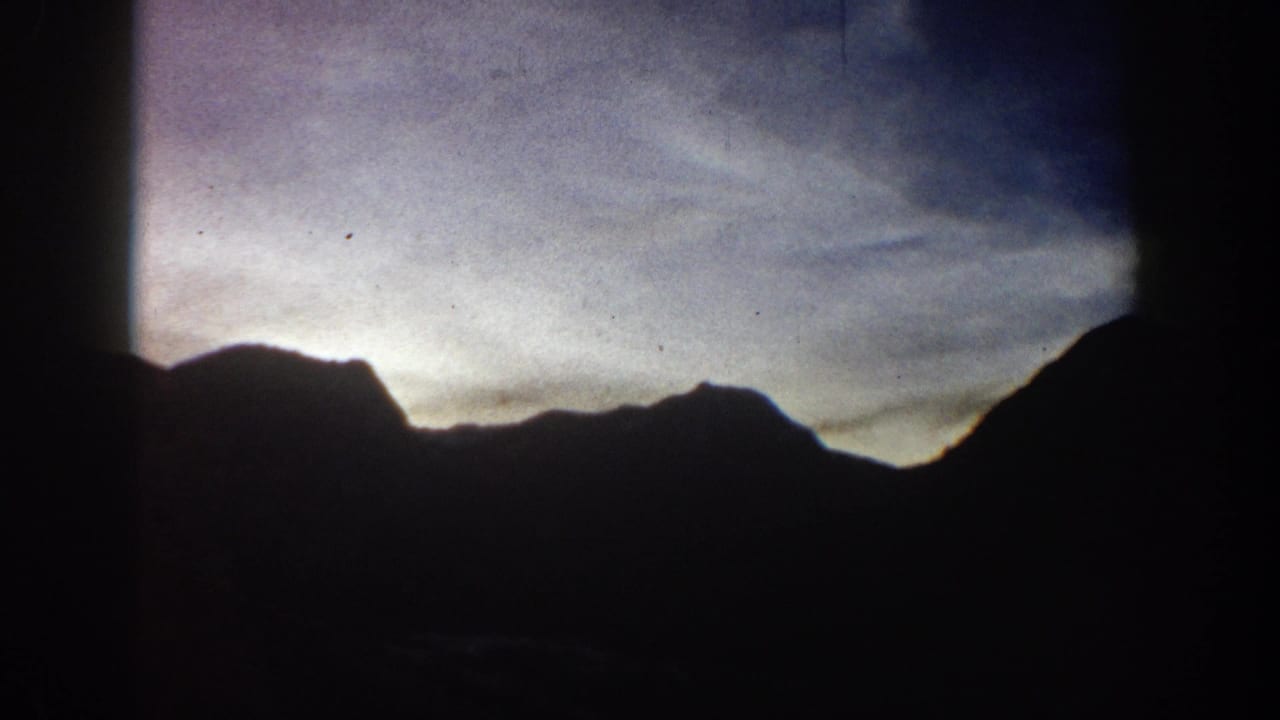 Mountain silhouette against a dusk sky, circa 1961 Aspen area; clip metadata indicates figures and a vintage vehicle appear in the full footage.