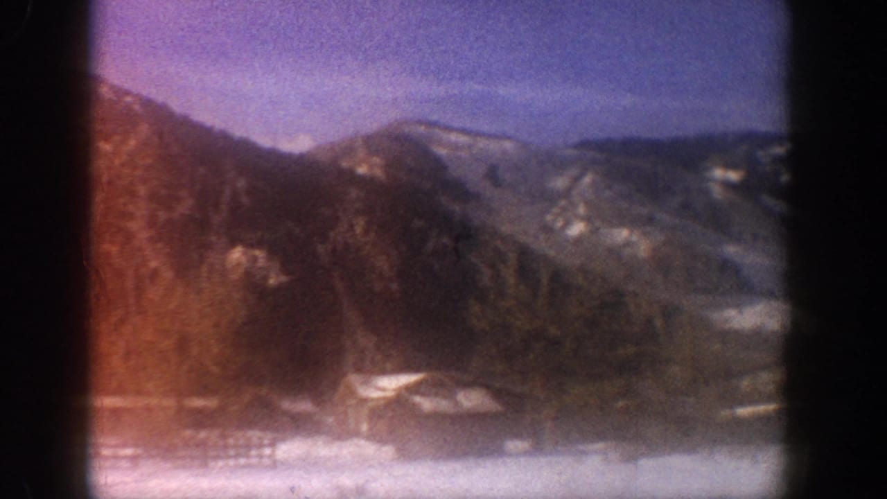 Snow-covered mountain slopes with severe magenta film dye-shift; small structures at valley base, Aspen Colorado area, circa 1961, 8mm.