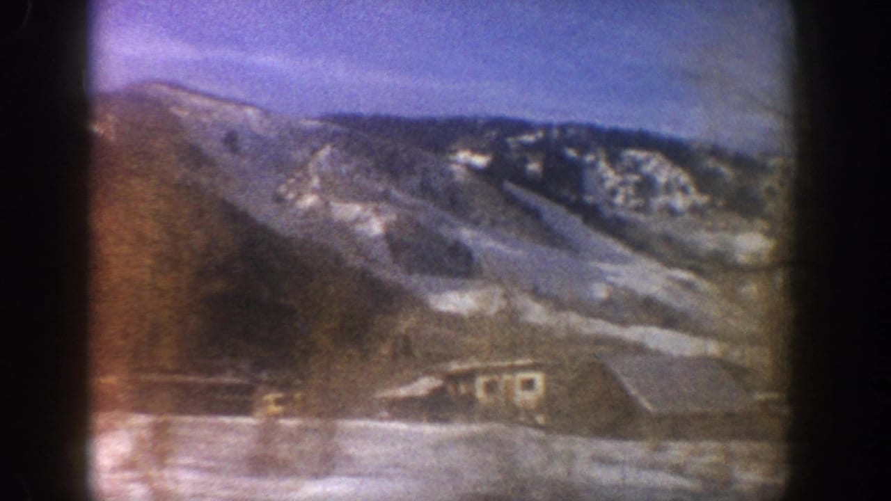 Continued camera pan across alpine valley with snow-covered slopes and structures at valley floor, Aspen Colorado area, circa 1961, 8mm.