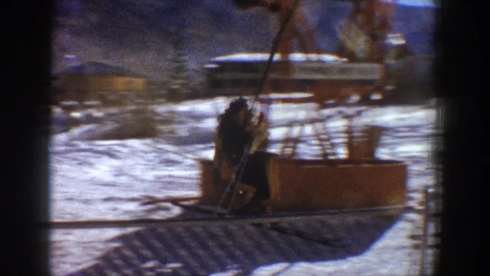 Close view of a person near orange lift machinery at the ski area base, Aspen Colorado area, circa 1961 8mm home movie.
