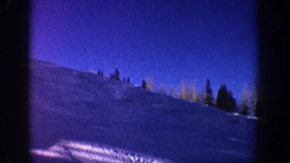 8mm panoramic frame of alpine mountain slope with evergreens on ridgeline, likely Aspen, Colorado area, circa 1961.