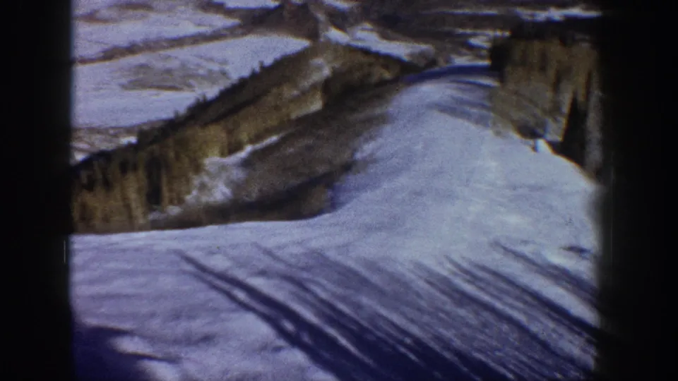 8mm home movie frame of a snow-filled mountain valley with shadow streaks across the snowfield and evergreen ridgeline, Aspen, Colorado area, circa 1961.