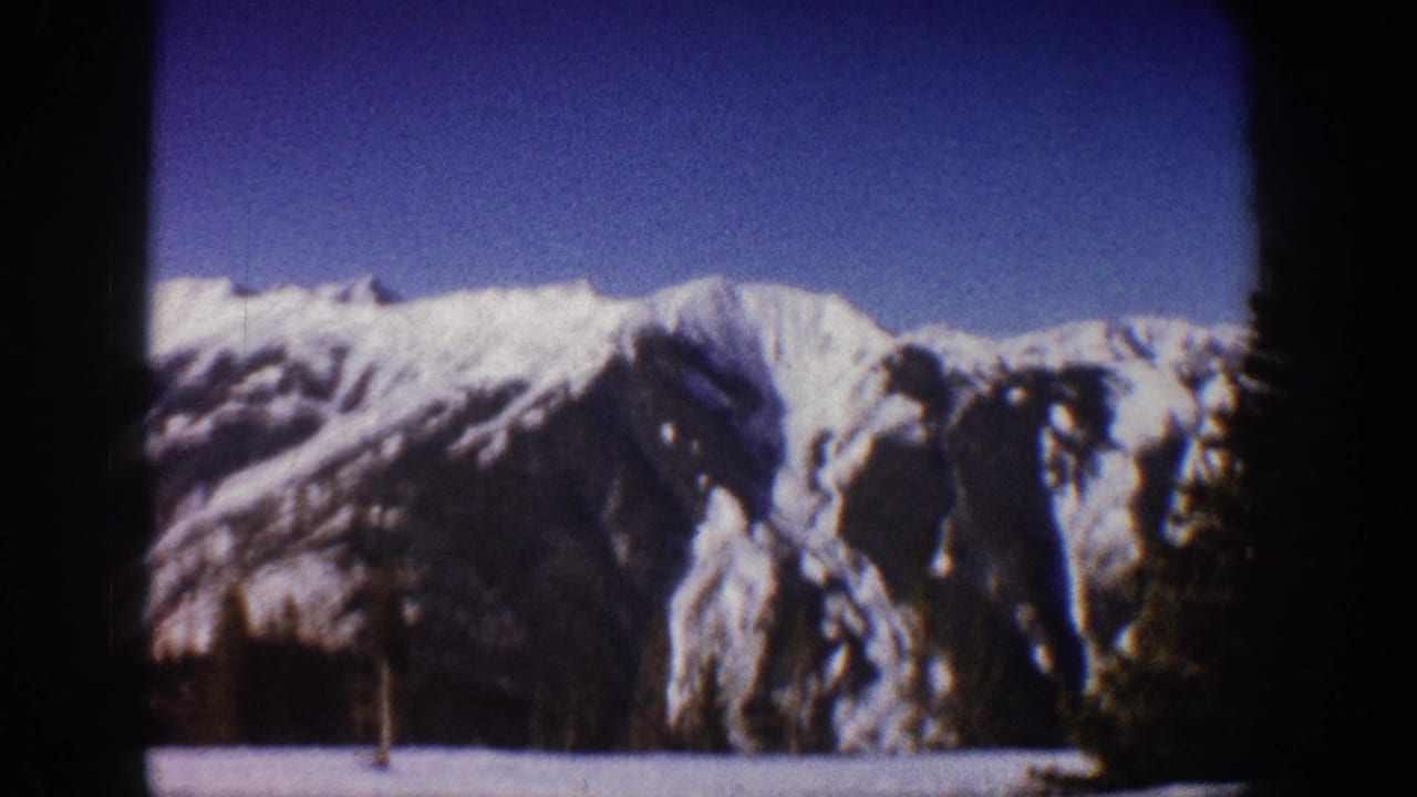 8mm home movie frame circa 1961 showing a snow-laden Rocky Mountain ridgeline under clear blue sky, Aspen, Colorado area.