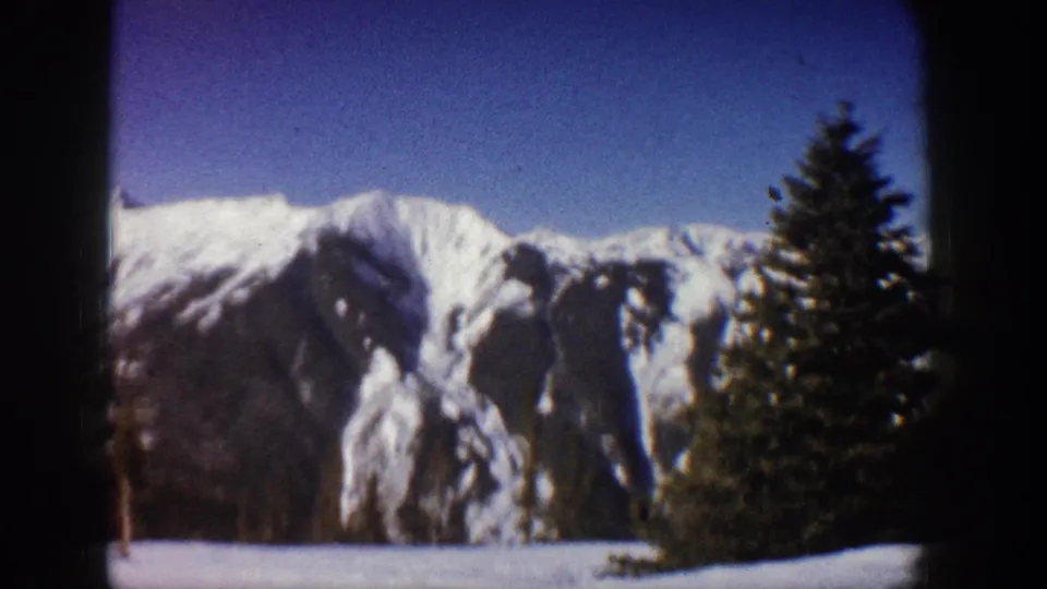 8mm home movie pan circa 1961 showing Colorado Rockies winter snowscape with a large spruce tree entering frame right, Aspen area.